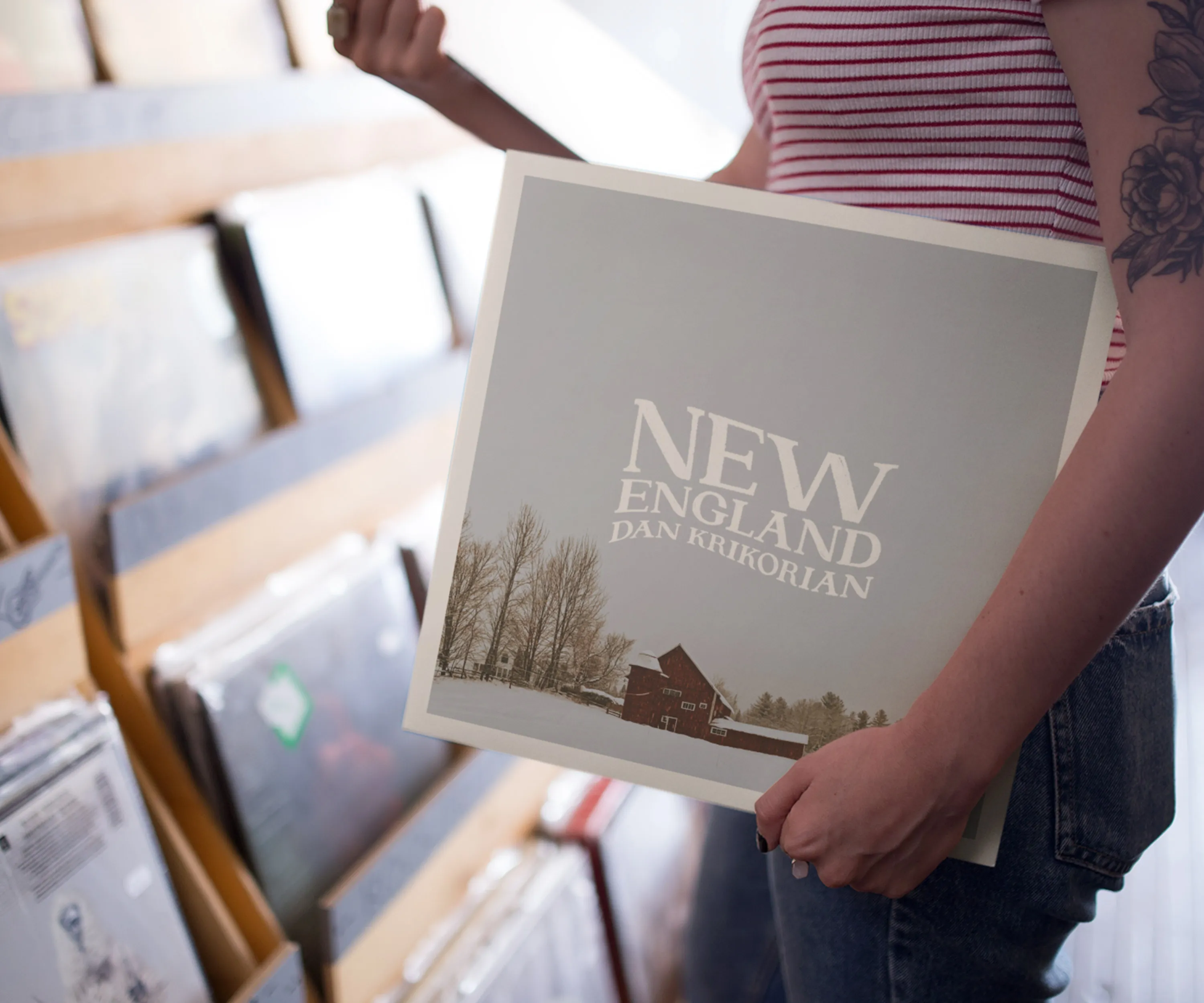 Person holding the "New England" record in a shop.