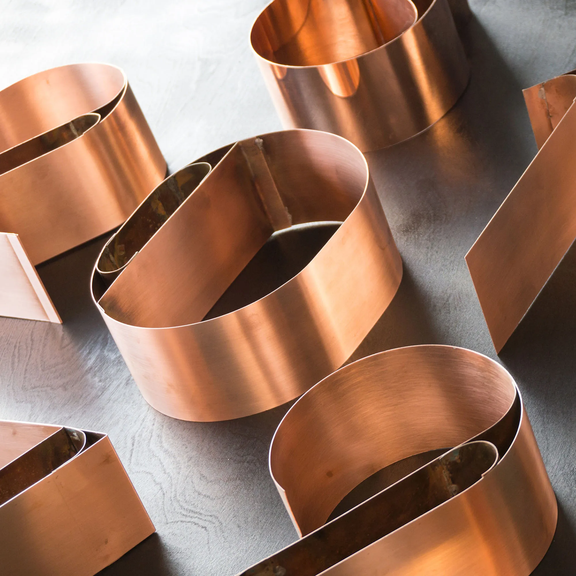 Curved polished copper house numbers arranged on a grey surface.