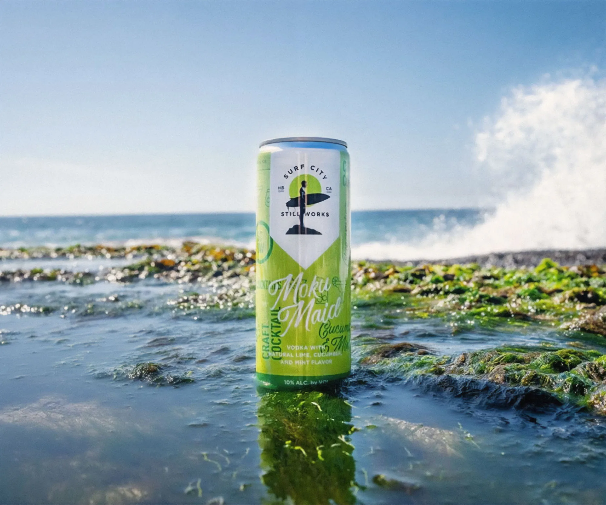 A hard seltzer can standing in a tide pool at the shoreline.